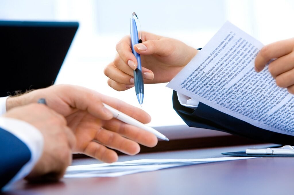 Signing documents beside a laptop